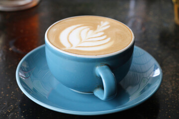 A cup of cappuccino served on an artistic black table