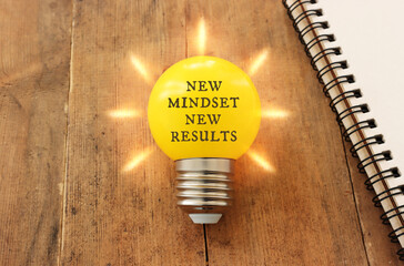 light bulb with the text new mindset in on wooden table - obrazy, fototapety, plakaty