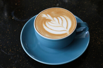 A cup of cappuccino served on an artistic black table