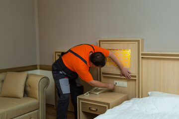 Male worker repairing electric socket hotel room.
