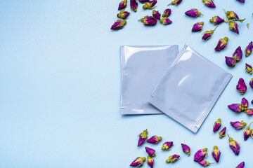 Two blue plastic tea bag sachets or envelopes with dry rosebuds.