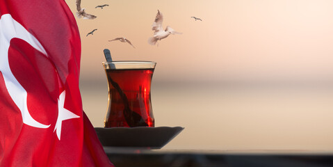 Traditional Turkish Glass of Tea. Photo Collage with Seagulls flying over a glass of tea against...