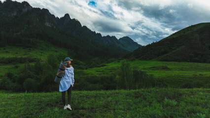 The girl admires the beautiful view of the mountains in summer time. Travel concept