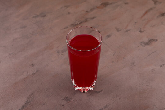 Glass of Salgam or fermented beet juice on brown background, selective focus. Popular Turkish drink. Traditional beverage made with water, purple carrot or turnip (juice)