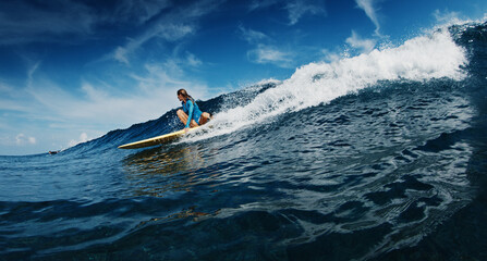 Slim woman surfer rides the wave. Woman surfs the ocean wave in the Maldives on yellow longboard