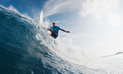 Pro surfer rides the wave. Young man surfs the ocean wave in the Maldives and aggressively turns on...