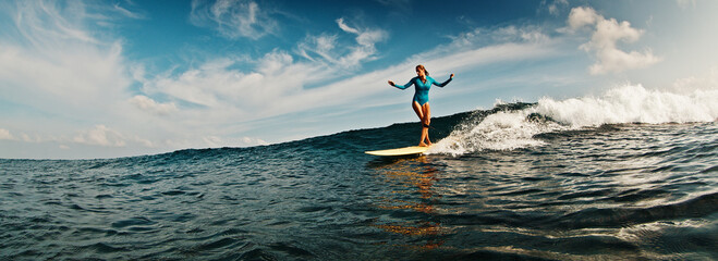 Slim woman surfer rides the wave. Woman surfs the ocean wave in the Maldives on yellow longboard - 581031959