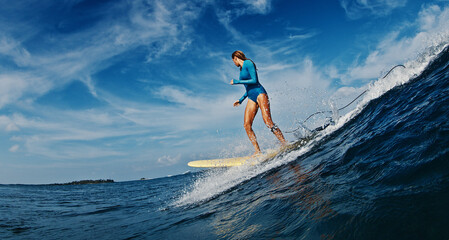 Slim woman surfer rides the wave. Woman surfs the ocean wave in the Maldives on yellow longboard