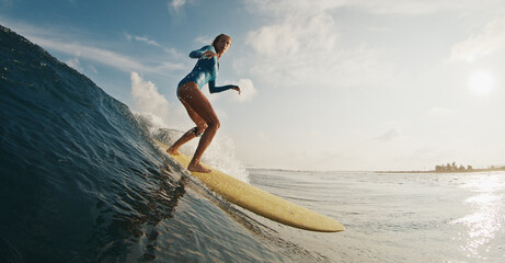 Slim woman surfer rides the wave. Woman surfs the ocean wave in the Maldives on yellow longboard - 581032107