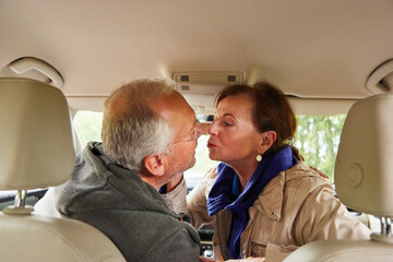 Romantic senior man and woman kissing in car