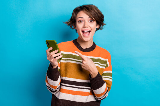 Photo of impressed woman with short hairstyle striped jumper directing at phone unbelievable unexpected isolated on blue color background