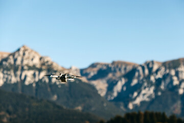 Drone flying over mountains on blue sky background.