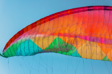 Background of colorful paraglider wing and blue sky.
