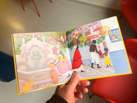 Paris, France - Oct 20, 2022: POV male hand reading a children's tales book La legende de Chico Rei - Brazilian tale by Beatrice Tanaka