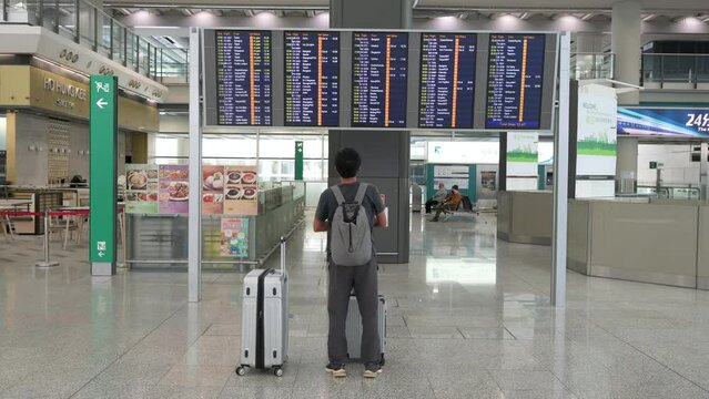 A passenger looks at a flight information screen where airline check-in desks are located in Hong Kong's international airport.