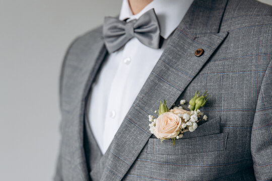 A man with a beard in a stylish suit with a watch on his arm fixes a bow tie. Morning of the groom. Close up detail of man suit for wedding