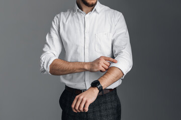 A man in a white shirt with rolled up sleeves is holding onto his collar. Watch on hand. Stylish...