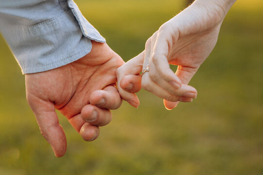 Hands close up of young guy and girl. Finger touch at sunset. Couple holding hands during love story