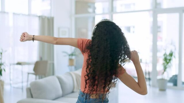 Dance, music and black woman with headphones in living room for relax, chilling and freedom on weekend. Wellness, smile and happy girl in house listening to song, streaming audio and dancing at home