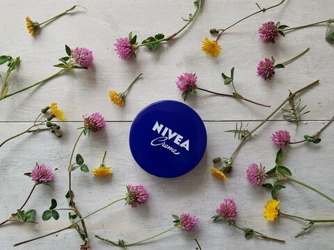 Nivea skin creme on white wooden background. Spring, flower, grass. 