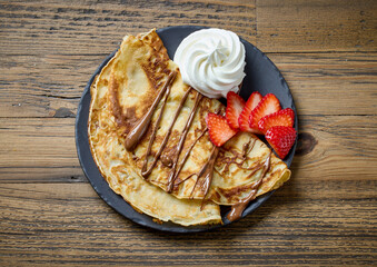 freshly baked crepes with whipped cream and strawberries
