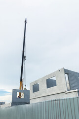 Onsite construction working on installation of housing precast wall with mobile crane for property business and construction industry presentation background.