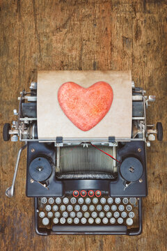 Top view of a vintage typewriter with red heart on a sheet of paper