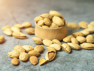shelled almonds on a dark stone table with a wooden spoon and a bowl. Almonds in a wooden bowl.