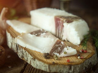Board with pork fat, on a rustic background Salo. Delicious salty lard with pepper. Place to copy.