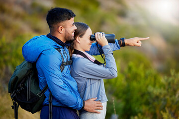 Binoculars, point and a couple bird watching in nature while hiking in the mountains together. Forest, ecology or sightseeing with a man and woman looking at the view while bonding on a hike - obrazy, fototapety, plakaty