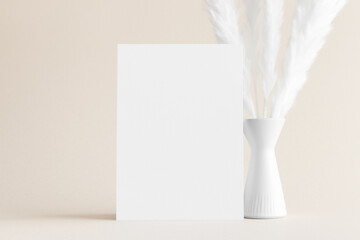 White invitation card mockup with a pampas decoration on the soft yellow background. 5x7 ratio,...