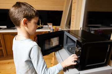 Fototapeta na wymiar Boy uses the microwave oven in the kitchen.