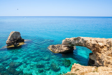 Fototapeta premium Love bridge near Ayia Napa in Cyprus. Natural rock arch formation known as Bridge of Lovers at Cape Greco. Sea caves on coastline between Agia Napa and Cavo Greco National park