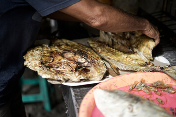 the process of cooking big grilled fish by a traditional Indonesian chef