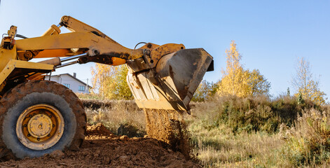 A large yellow wheel loader aligns ground for a new building. Land preparation for the auction or...