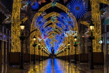 Two women walking down promenade with  decorative Carnival lights at night. Carnival is a week long festival in Malaga, Spain with parades along Larios Street and daily events in Constitution Square.