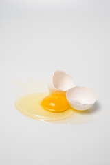 A broken egg on a white background. The protein and yolk flowed out of a broken egg close-up. Vertical photograph of cracked egg. Place for infographics and text. 