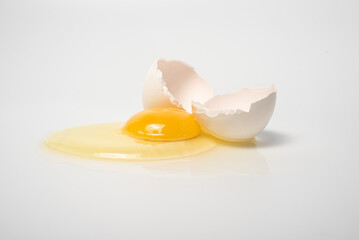 A broken egg on a white background. The protein and yolk flowed out of a broken egg close-up. Horizontal photograph of cracked egg. Place for infographics and text. 