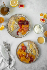 Homemade crepes, blinis, pancakes served on ceramic plates with poppy seeds and citrus fruits -...