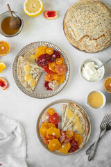Homemade crepes, blinis, pancakes served on ceramic plates with poppy seeds and citrus fruits - oranges, lemons, bloody oranges. Top view.