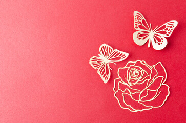 A carve the white paper butterfly and flower on a red cardboard background.