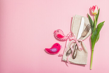 Fototapeta na wymiar Romantic table setting with pink tulips and handmade birds. Vintage cutlery, fresh flowers, napkin