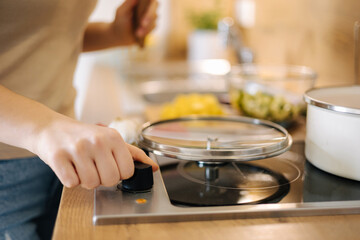 Human hand turn on electric stove. Home made food concept 