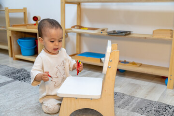 Toddler writing with oil pencil on chair