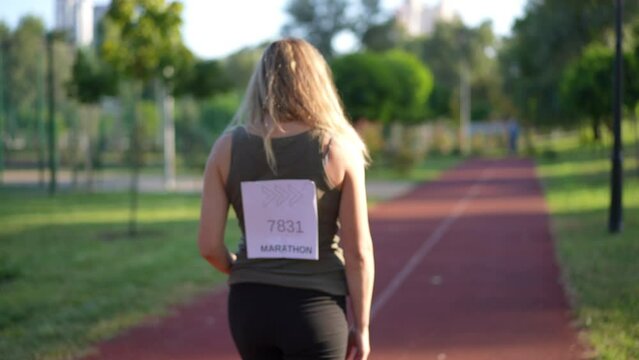 Smiling satisfied woman gesturing high-five with friend passing on sports track after marathon. Portrait of positive Caucasian sportswoman rejoicing with friend outdoors. Sport and motivation concept