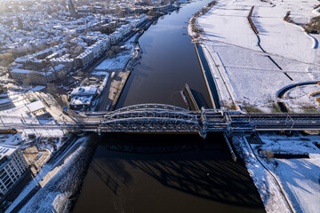 Steel draw bridge over river IJssel and white floodplains of Dutch Hanseatic medieval tower town...