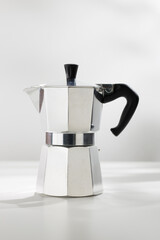 Moka pot espresso machine on a white table.