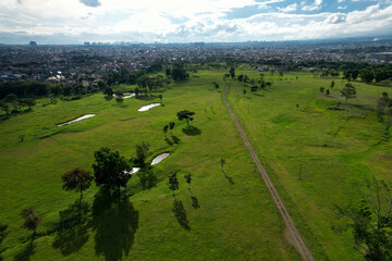 Aerial view of large green fields in adjoining settlements and daylight