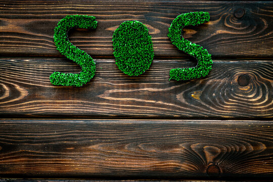 Word SOS made of green grass. Save the Earth planet ecology concept.