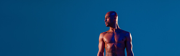 Muscular man doing exercise with weight dumbbells on studio background. Strength and motivation